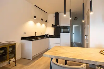 a kitchen with white cabinets and a wooden table at Hoorn Centre - Catching Hoorn in Hoorn