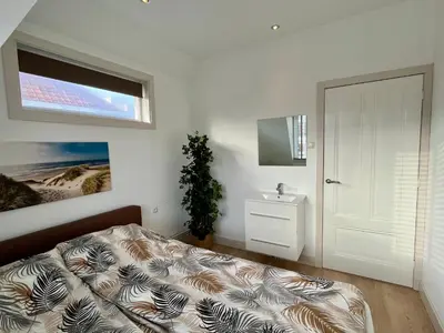 a bedroom with a bed and a sink and a window at Vakantiehuis Pollux 6 pers 300m van het strand in Noordwijk aan Zee