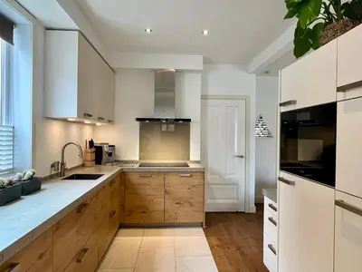 a kitchen with white counters and wooden cabinets at Vakantiehuis Pollux 6 pers 300m van het strand in Noordwijk aan Zee