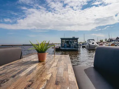 a wooden table with a potted plant on a dock at Houseboat Uitgeest in Uitgeest