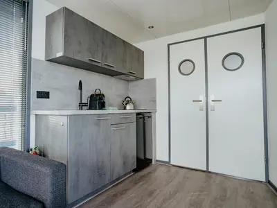 a kitchen with a pivot door in a room at Houseboat Uitgeest in Uitgeest