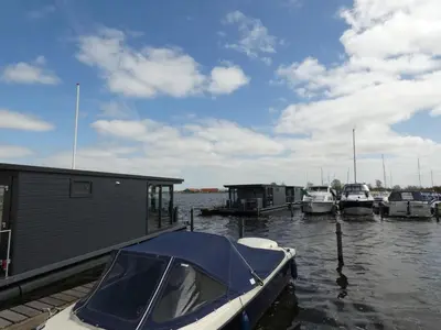 a boat is docked at a dock with other boats at Houseboat Plus Uitgeest in Uitgeest