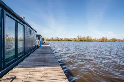 a house on a dock on a body of water at Houseboat Plus Uitgeest in Uitgeest