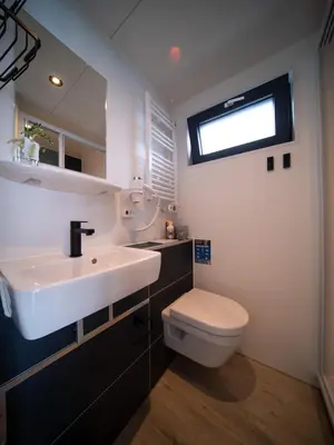 a bathroom with a sink and a toilet and a window at Houseboat Plus Uitgeest in Uitgeest