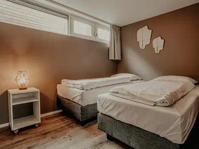 a bedroom with two beds and a table with a lamp at Houseboat Woude Uitgeest in Uitgeest
