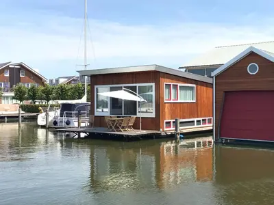 a house on a dock on a body of water at Houseboat Woude Uitgeest in Uitgeest