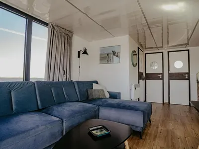 a living room with a blue couch and a table at Houseboat Campi Uitgeest in Uitgeest