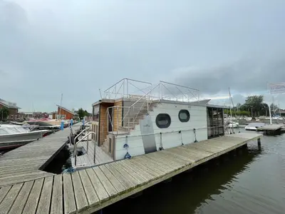 a boat docked next to a wooden dock at Houseboat Campi Uitgeest in Uitgeest