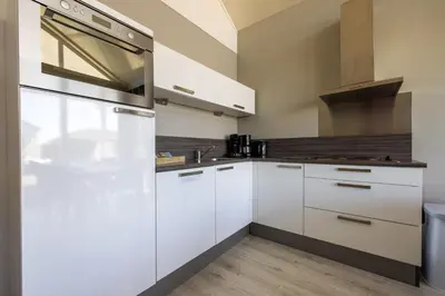 a kitchen with white cabinets and a stainless steel refrigerator at Wilgenroos 6P - Lijsterlaan 198 in Wervershoof