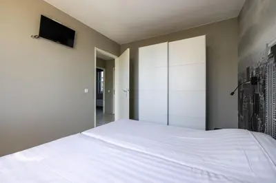 a bedroom with a white bed and a tv on the wall at Wilgenroos 6P - Lijsterlaan 198 in Wervershoof