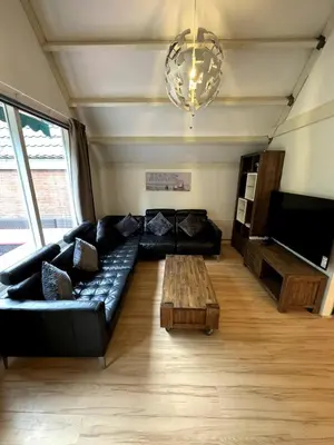 a living room with a black leather couch and a coffee table at 3 bedrooms Family House till 6 p Near Amsterdam & Sea in Opmeer