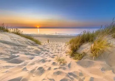 a sandy beach with a sunset in the background at 3 bedrooms Family House till 6 p Near Amsterdam & Sea in Opmeer