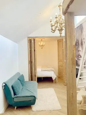 a living room with a blue couch and a bedroom at La Bastide in Heiloo