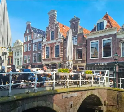 a bridge over a canal with people sitting at tables at Slapen bij De Buren in Alkmaar