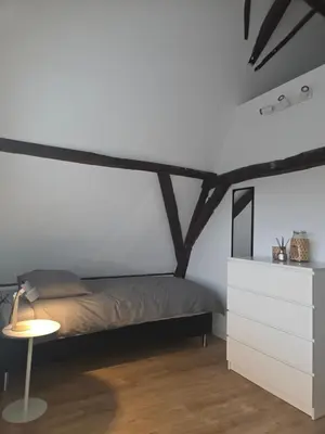a white bedroom with a bed and a table at Slapen bij De Buren in Alkmaar