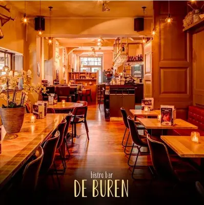 a restaurant with tables and chairs and a kitchen at Slapen bij De Buren in Alkmaar