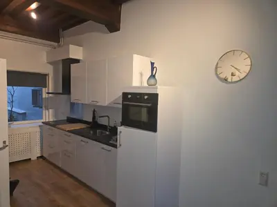 a kitchen with a refrigerator and a clock on the wall at Slapen bij De Buren in Alkmaar