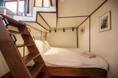 a small room with a bed and a staircase at Marie's Houseboat in Amsterdam