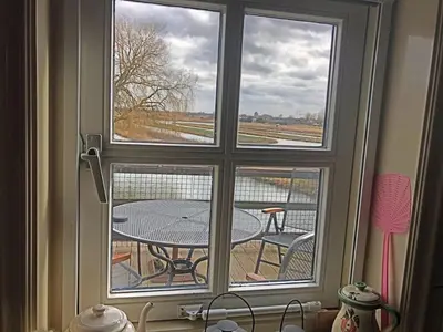 a window with a table and a view of a field at Apartment by the water in Broek op Langedijk