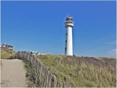 a lighthouse on top of a hill with a fence at Apartment by the water in Broek op Langedijk