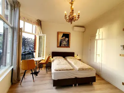 a bedroom with a bed and a table and a chandelier at As Home in Amsterdam