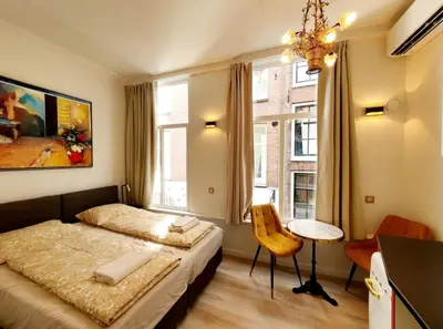 a bedroom with two beds and a table and a chair at As Home in Amsterdam
