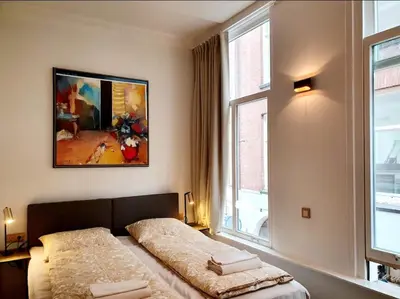 a bedroom with two beds and a large window at As Home in Amsterdam