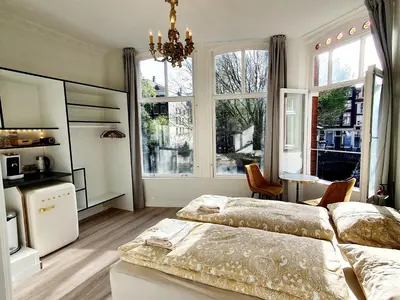 a bedroom with two beds and a large window at As Home in Amsterdam