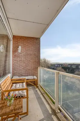 a balcony with wooden benches and a brick wall at Comfortable Stay Near The Coast in Burgerbrug