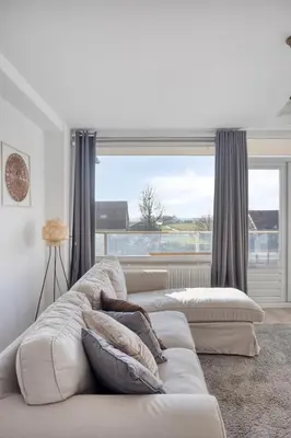 a living room with a couch and a large window at Comfortable Stay Near The Coast in Burgerbrug