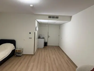 a bedroom with white walls and a bed and a wooden floor at Lely in Lelystad