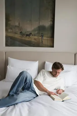 a man laying on a bed reading a book at Dam Residence - Boutique Hotel in Zaandam