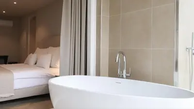 a bath tub in a bathroom with a bed at Dam Residence - Boutique Hotel in Zaandam
