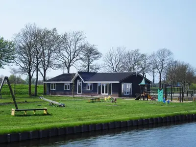 a house with a playground next to the water at De Beemster | Group accommodation near Amsterdam in West-Graftdijk
