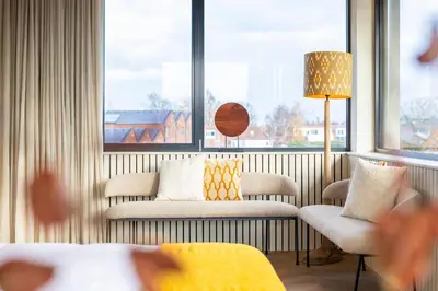 a hotel room with a couch and chairs and windows at Seinhuis Post VI in Amersfoort