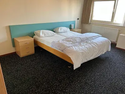 a bedroom with a large bed with a blue headboard at Fokkeboom in Almere