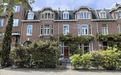 a large brick house with bushes in front of it at Top Floor Apartment Vondelpark in Amsterdam