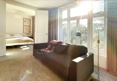 a living room with a couch and a bed and a window at Top Floor Apartment Vondelpark in Amsterdam