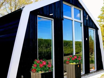 a black and white building with two windows and flowers at Holiday Home Markermeerlogies by Interhome in Bovenkarspel
