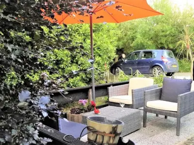 a patio with an umbrella and chairs and a table at Holiday Home Markermeerlogies by Interhome in Bovenkarspel