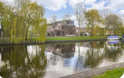 a reflection of a building in a lake with trees at Studio Mokum in Amsterdam