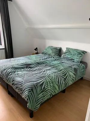 a bed with a green and white comforter and pillows at Botanico - family house in Egmond aan Zee