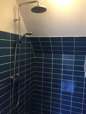 a blue tiled shower with a shower head in a bathroom at Botanico - family house in Egmond aan Zee