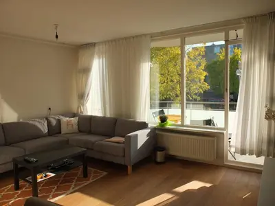 a living room with a couch and a large window at Cozy 2 Bedroom Home Away from Home in Amsterdam