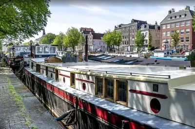 a boat in a canal in a city at Houseboat Avontuur in Amsterdam