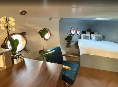 a bedroom with a bed and a desk and a table at Houseboat Avontuur in Amsterdam