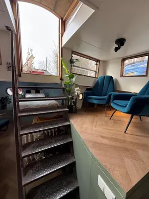 a room with stairs and blue chairs in a house at Houseboat Avontuur in Amsterdam