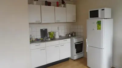 a kitchen with white cabinets and a white refrigerator at Studio in Ons Belang