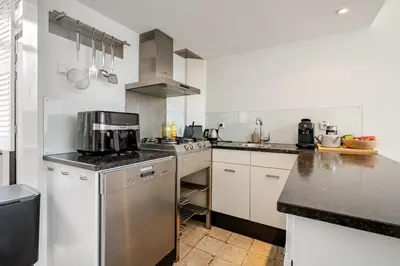 a kitchen with white cabinets and a stove top oven at Charming Loft with Free Parking and 15 mins to AMS in Vinkeveen