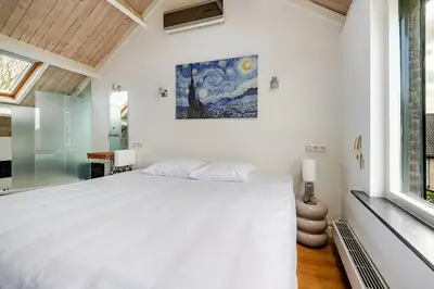 a bedroom with a large white bed and a window at Charming Loft with Free Parking and 15 mins to AMS in Vinkeveen